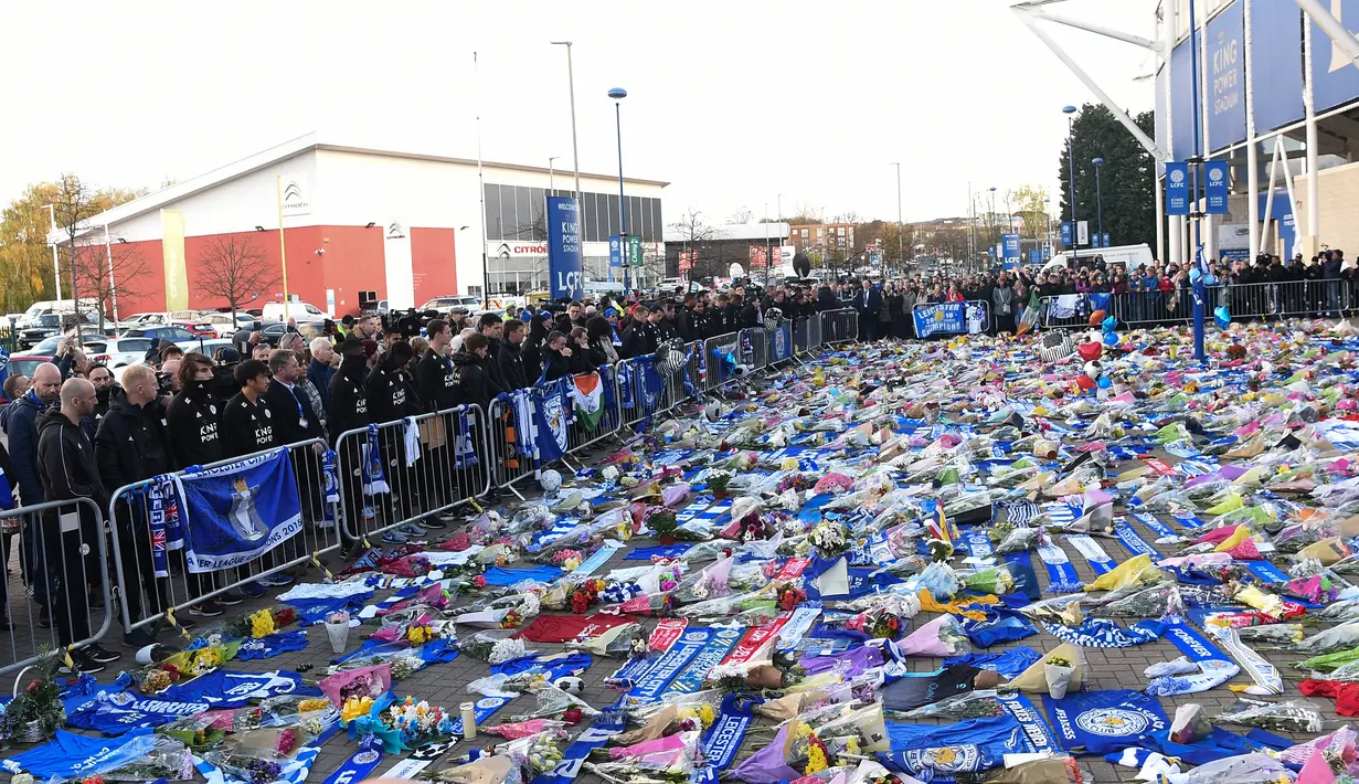 Pemain dan staf Leicester City (kiri) memberi penghormatan kepada korban kecelakaan helikopter yang menewaskan pemilik Leicester City Vichai Srivaddhanaprabha di luar Stadion King Power, Inggris, Senin (29/10). (Paul Ellis/AFP)
