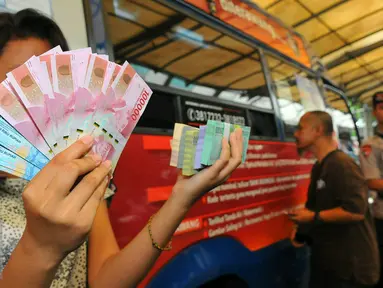 Seorang wanita menunjukan beberapa mata uang baru di Blok M, Jakarta, Senin (19/12). Bank Indonesia (BI) hari ini meluncurkan 11 uang rupiah Emisi 2016 dengan gambar pahlawan baru. (Liputan6.com/Angga Yuniar)