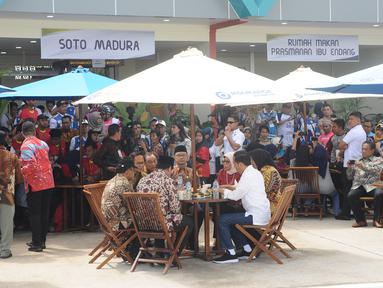 Presiden Joko Widodo (Jokowi) berbincang sambil menjajal makanan saat meninjau Rest Area 538 seusai meresmikan ruas Tol Sragen-Ngawi, Jawa Tengah, Rabu (28/11). Jokowi duduk semeja dengan kepala serta pimpinan daerah setempat. (Liputan6.com/Angga Yuniar)