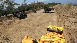Petugas membawa jenazah korban gempa dan tsunami untuk dimakamkan massal di Palu, Sulawesi Tengah, Senin (1/10). (AP Photo/Tatan Syuflana)