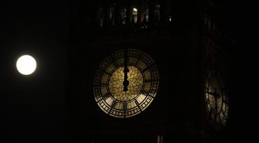 Bulan purnama pertama tahun ini yang dikenal sebagai Wolf Moon terlihat di balik jam saat perbaikan Menara Elizabeth, yang dikenal sebagai Big Ben dan Gedung Parlemen, di London, Senin (17/1/2022). Wolf Moon adalah sebutan untuk bulan purnama pertama di Januari. (AP Photo/Matt Dunham)