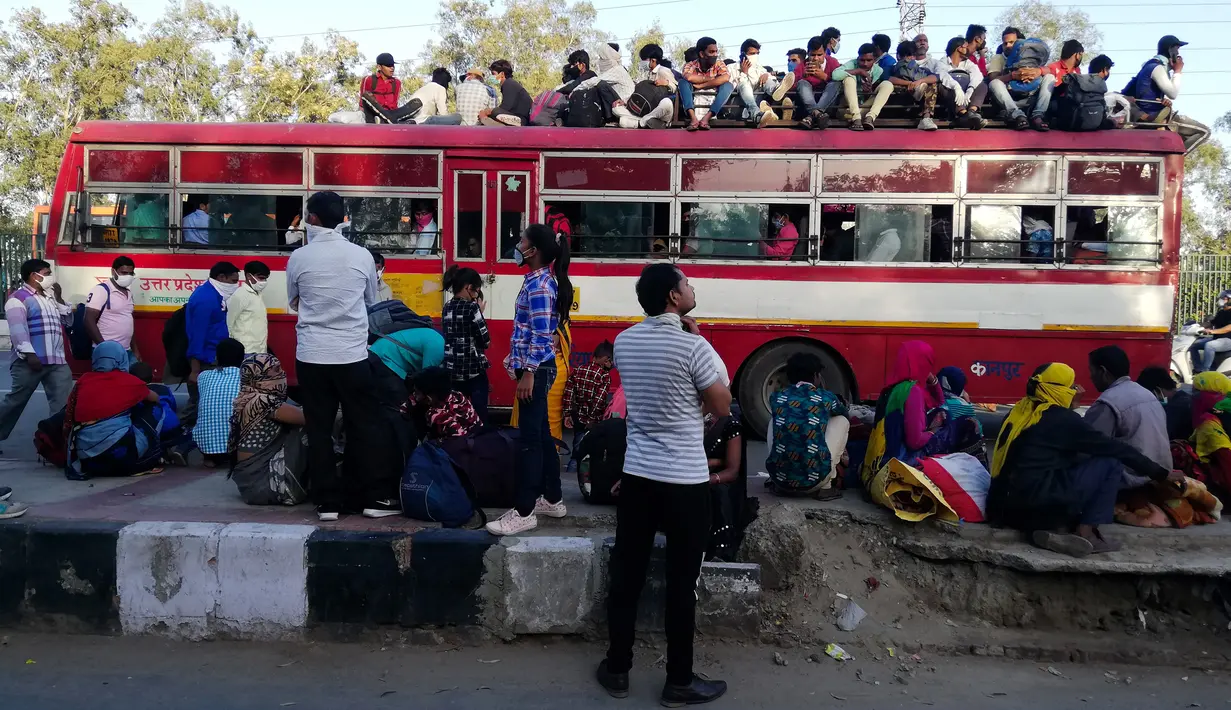 Pekerja migran dan anggota keluarga mereka berkumpul di luar terminal bus Anand Vihar untuk pulang ke kampung halamannya, di New Delhi, Sabtu (28/3/2020). Ribuan orang meninggalkan New Delhi setelah pemerintah India memberlakukan lockdown untuk mencegah penyebaran COVID-19. (Bhuvan BAGGA/AFP)