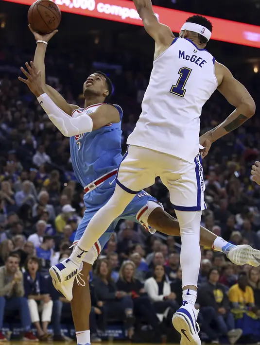 Gaya pemain Sacramento Kings, Skal Labissiere (kiri) mencetak poin saat melewati adangan pemain Warriors, JaVale McGee pada laga NBA basketball game di Golden 1 Center, Oakland, California, (16/3/2018). King menang 98-93. (AP/Ben Margot)