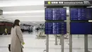 Penumpang berjalan dekat layar jadwal kedatangan penerbangan internasional di Bandara Narita, Tokyo, Kamis (2/12/2021). Maskapai-maskapai internasional diminta menangguhkan reservasi baru pada semua penerbangan masuk ke Jepang hingga akhir Desember terkait varian Omicron. (AP Photo/Hiro Komae)