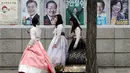 Sejumlah wanita berjalan dekat poster calon presiden Korea Selatan (Korsel) di Seoul, Selasa (9/5). Hari ini, warga Korsel mulai memberikan hak suaranya untuk memilih presiden baru setelah pemakzulan Park Geun-hye. (Jeon Heon-kyun/Pool Photo via AP)