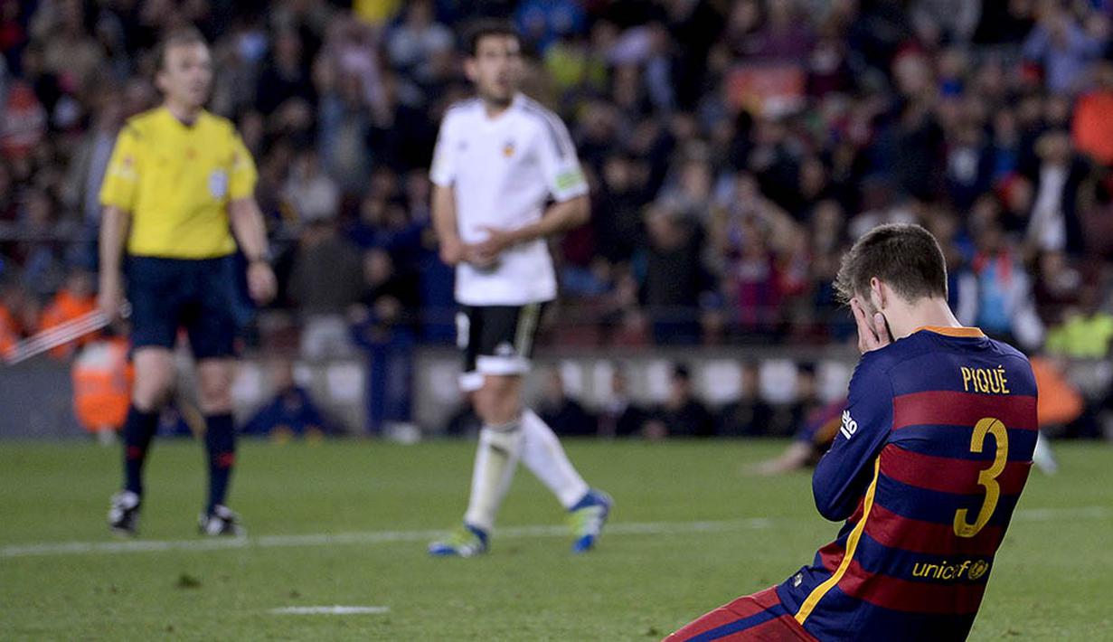 Bek Barcelona, Gerard Pique, tertunduk penuh kecewa usai takluk dari Valencia pada laga La Liga Spanyol di Stadion Camp Nou, Barcelona, Minggu (18/4/2016). Sebelumnya kekalahan ini, Barca juga sudah tersingkir dari Liga Champions. (AFP/Josep Lago)