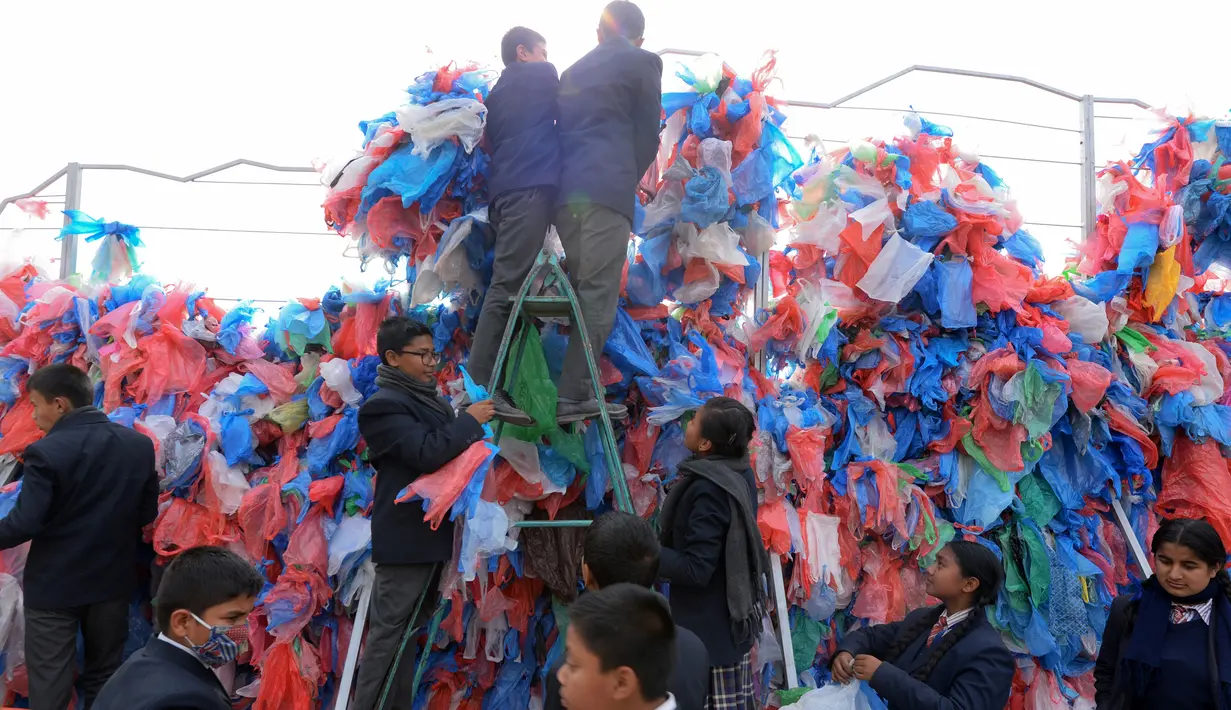 Relawan Nepal dan siswa sekolah membuat replika Laut Mati dari plastik daur ulang di Kathmandu pada 5 Desember 2018. Mereka mengikat 100.000 kantong plastik bekas berwarna-warni untuk upaya pembuatan rekor dunia baru. (PRAKASH MATHEMA / AFP)
