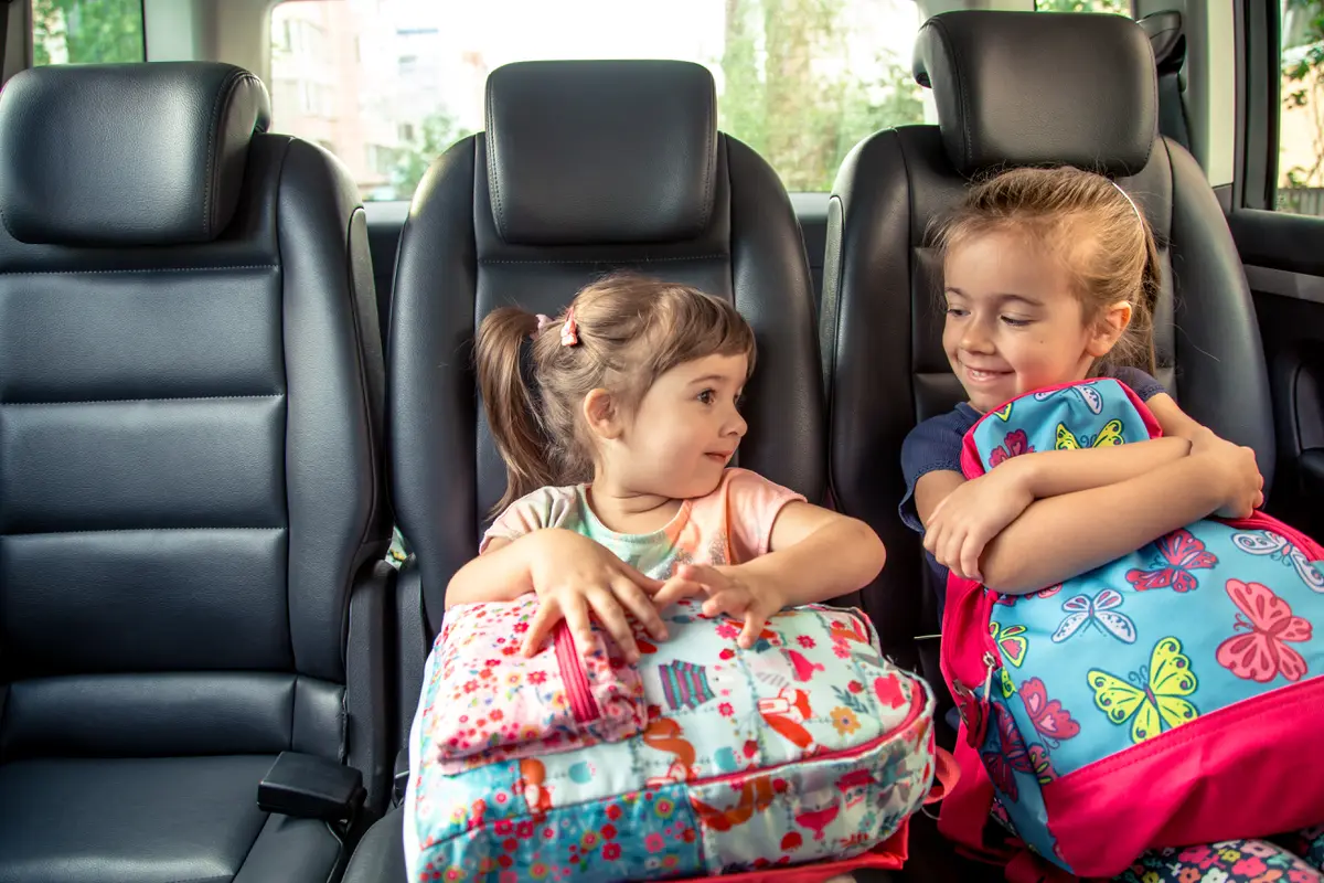 Dua orang anak perempuan memegang tas ransel di dalam mobil (Foto Dok: Freepik/pvproductions)