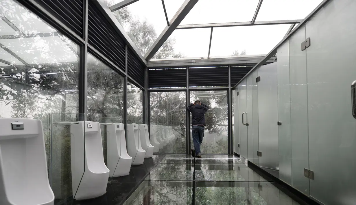Pengunjung berada di dalam toilet di sebuah taman di Changsha, Tiongkok, Kamis (29/9). Tak hanya dinding yang terbuat dari kaca, lantainya pun juga terbuat dari kaca transparan. (REUTERS/Stringer)