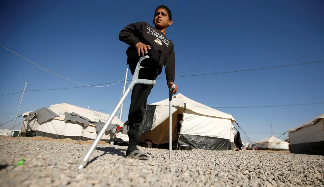 Jasim Abudllah saat berada di sekitar kamp pengungsian Debaga, Erbil, Irak (24/11). Bocah berumur 13 tahun tersebut, terpaksa harus kehilangan kaki kanannya akibat terkena serangan udara di Baiji. (Reuters/Mohammed Salem)