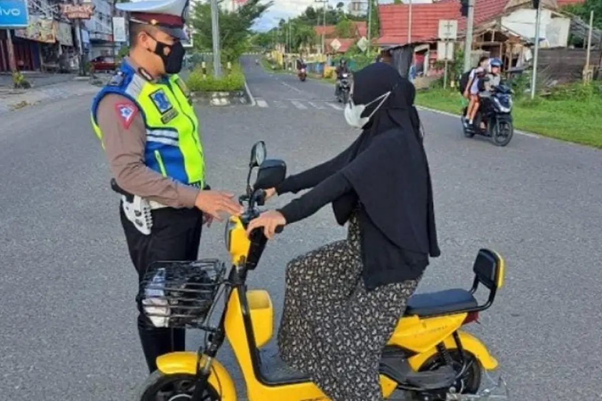 Petugas kepolisian tengah memberikan informasi kepada pengguna sepeda listrik