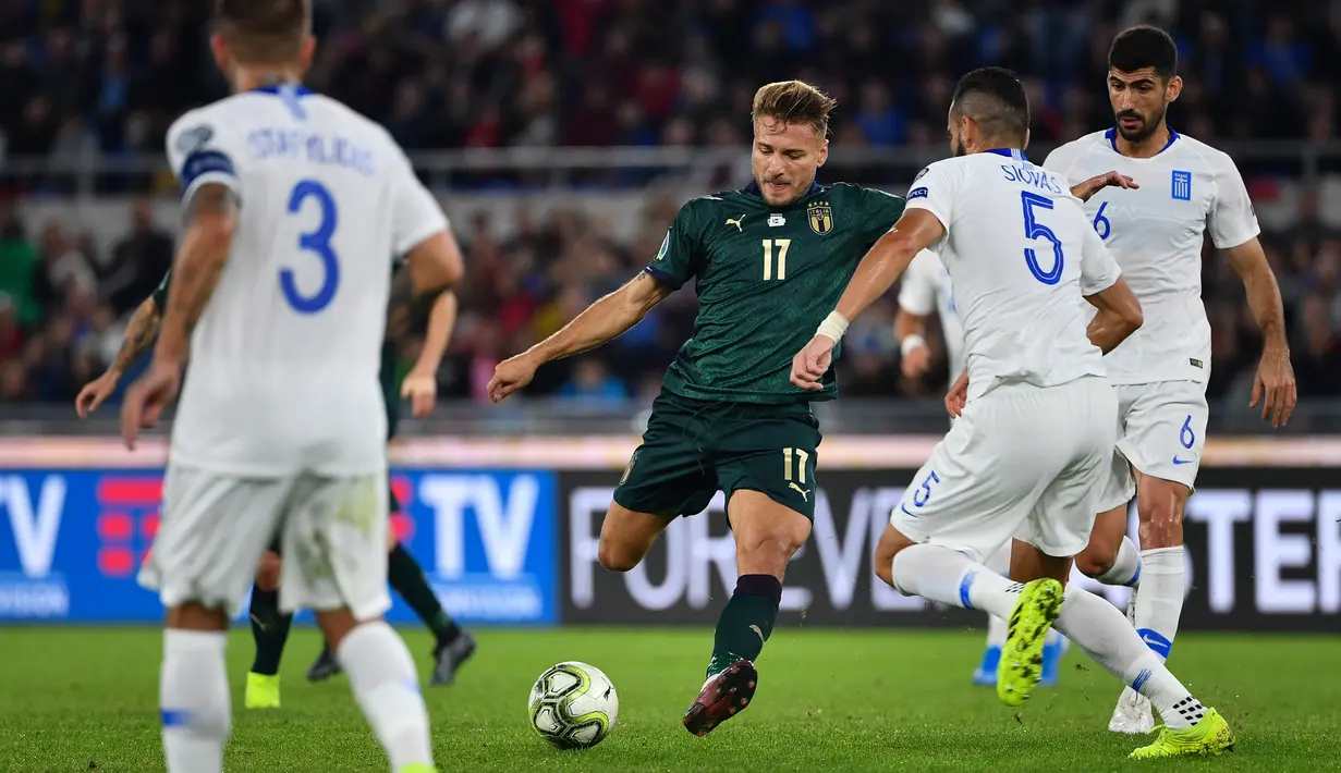 Striker timnas Italia, Ciro Immobile berebut bola dengan pemain Yunani, Dimitris Siovas dan Andreas Bouchalakis pada pertandingan grup J babak kualifikasi Piala Eropa 2020 di Stadio Olimpico, Sabtu (12/10/2019). Italia lolos ke putaran final setelah mengalahkan Yunani, 2-0. (Alberto PIZZOLI / AFP)