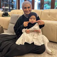 Krisdayanti dalam kesempatan lainnya terlihat memangku Ameena yang tampil gemas dalam balutan dress putih dan hijab hitam. Krisdayanti sendiri tampil dengan abaya hitam dan hijab cokelat. [Foto: Instagram/krisdayantilemos]