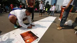 Warga menandatangani Petisi Penolakan Kenaikan Tarif Dasar Listrik di kawasan Bundaran HI, Jakarta, Minggu (7/5). Mereka menolak kebijakan kenaikan tarif dasar listrik yang diberlakukan per 1 Mei lalu. (Liputan6.com/Helmi Fithriansyah)