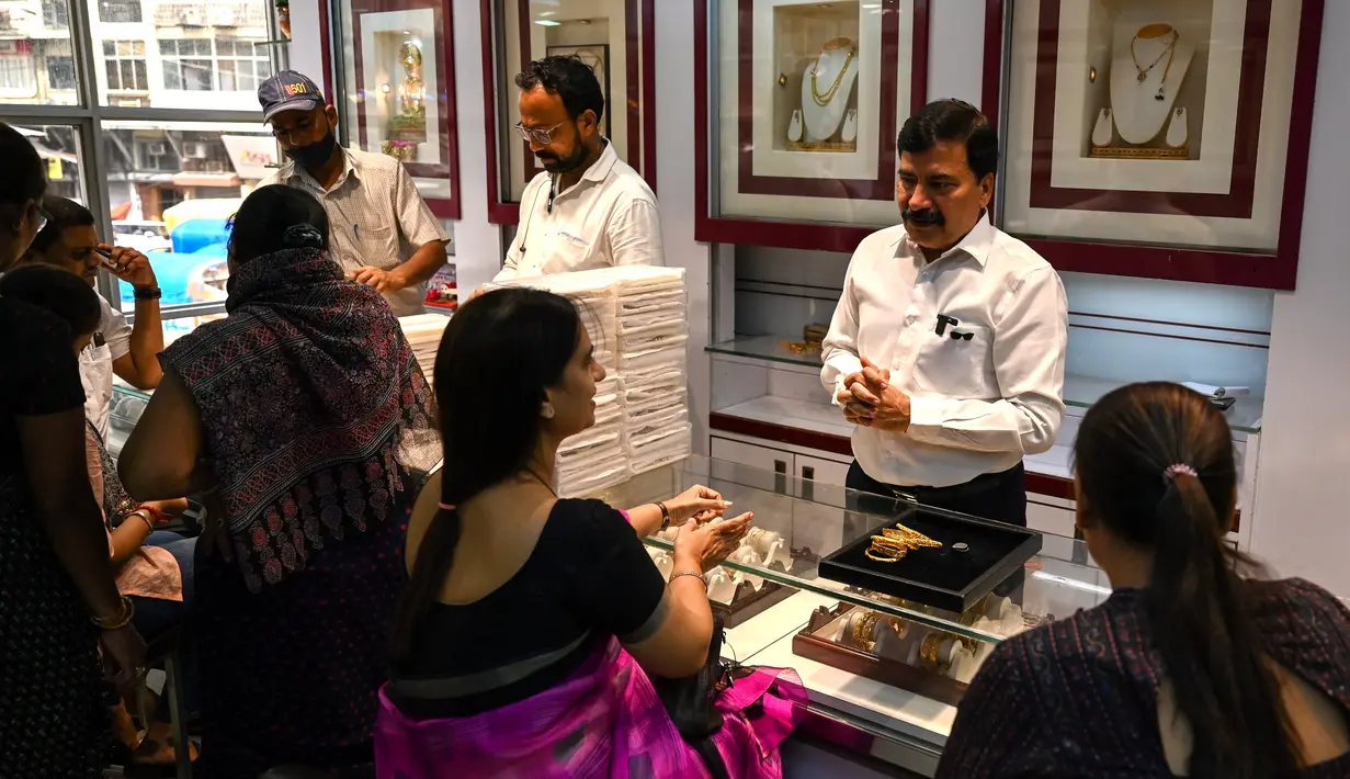 Gambar diambil pada 11 Agustus 2021 menunjukkan seorang manajer toko perhiasan berbicara dengan pelanggan di Mumbai, India. Putus asa mendapatkan uang tunai, banyak keluarga dan usaha kecil menjual perhiasan emas sebagai jaminan untuk mendapatkan pinjaman jangka pendek. (Punit PARANJPE/AFP)