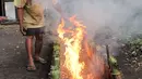 Pak Pian memperbesar api saat membakar lemang di sebuah tanah kosong di Jakarta, Minggu (27/5). Pak Pian mengaku dapat memproduksi hingga 100 buah lemang per hari di bulan Ramadan. (Merdeka.com/Iqbal S Nugroho)