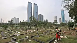Petugas kebersihan memotong rumput makam di TPU Karet Bivak, Jakarta, Kamis (12/7). Kurang lebih 100 jenazah dimakamkan setiap harinya di wilayah Jakarta. (Merdeka.com/Iqbal Nugroho)