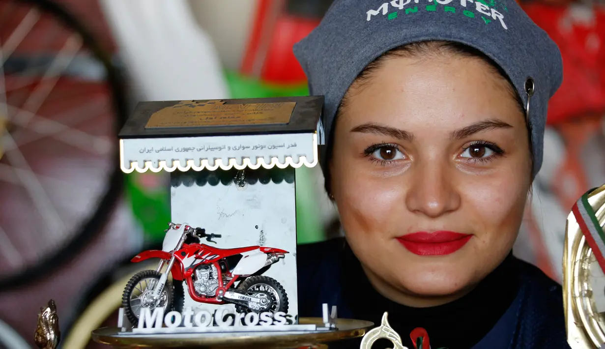 Behnaz Shafiei berpose di dekat tropi di Parand, Teheran (27/2). Crosser cantik 28 tahun itu merupakan pembalap perempuan pertama di Iran. (AFP PHOTO/Atta Kenare)