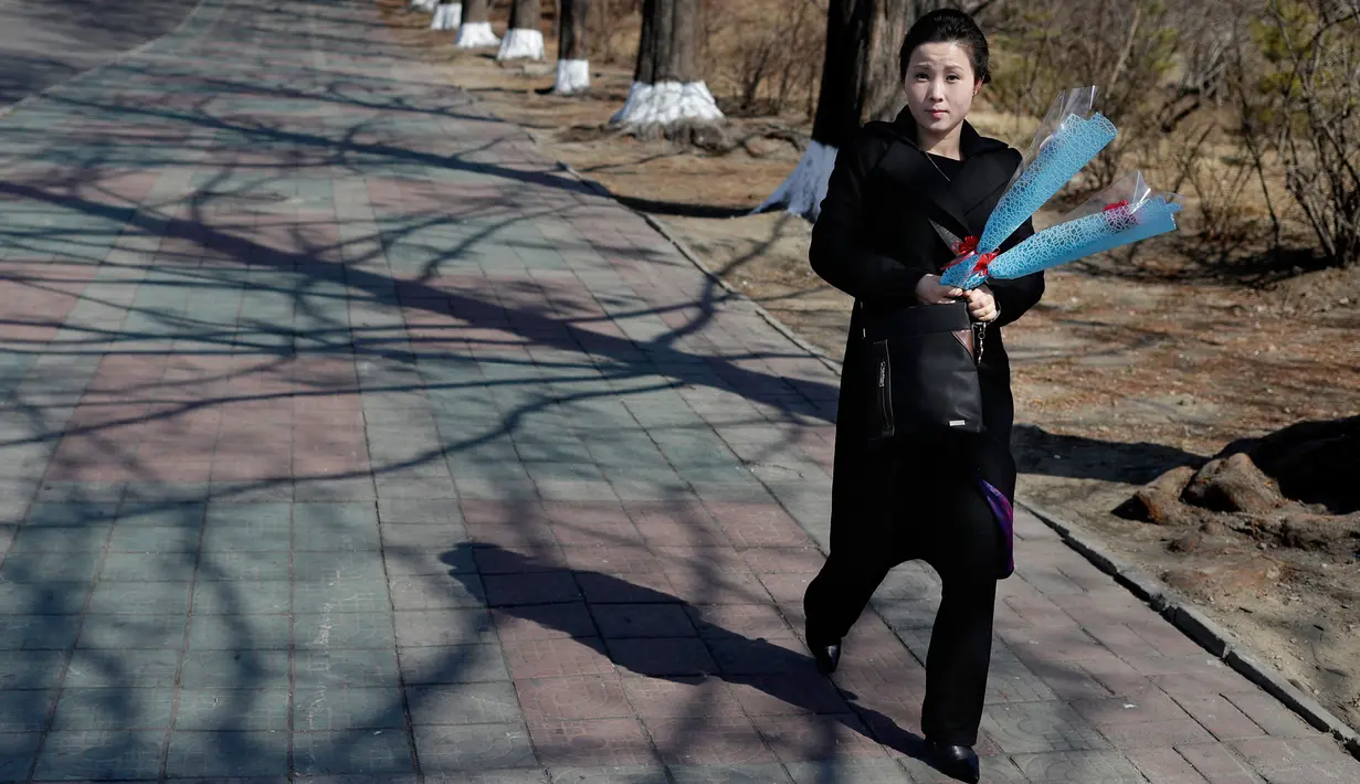 Seorang wanita membawa bunga saat menandai Hari Perempuan Internasional di Pyongyang, Korea Utara, Jumat (8/3). Hari Perempuan Internasional jatuh pada tanggal 8 Maret setiap tahunnya. (AP Photo/Dita Alangkara)