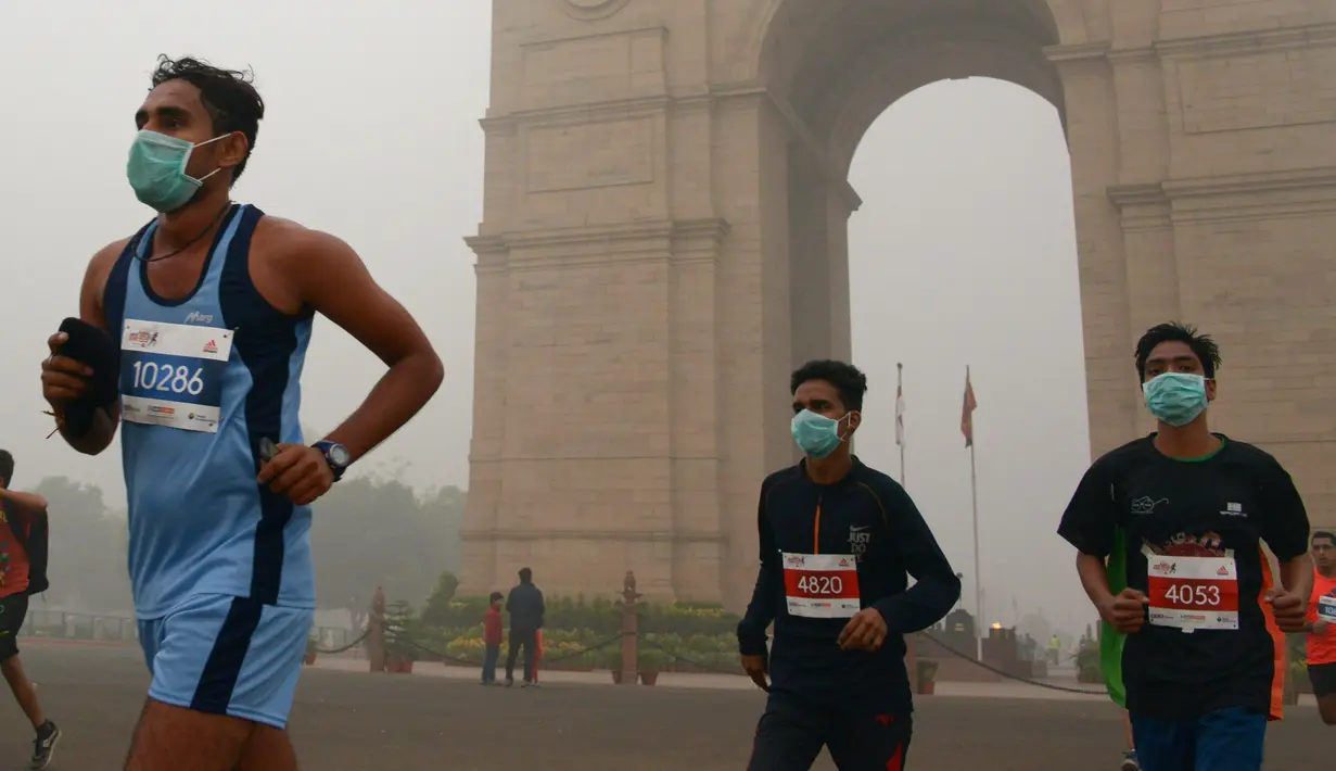 Peserta yang mengikuti lomba New Delhi 10K berlari di depan India Gate menggunakan masker di New Delhi, India (31/10). Partikel ini dapat menyebabkan batuk, bersin hingga sesak napas. (AFP/Dominique Faget)