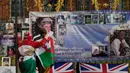 Sepasang kekasih, terbungkus bendera Welsh, melihat potret dan pesan peringatan untuk Putri Diana yang dipajang di gerbang Istana Kensington, London, Rabu (31/8/2022). Hari ini menandai peringatan 25 tahun kematian Putri Diana dalam kecelakaan mobil di Paris. (AP Photo/Alastair Grant)