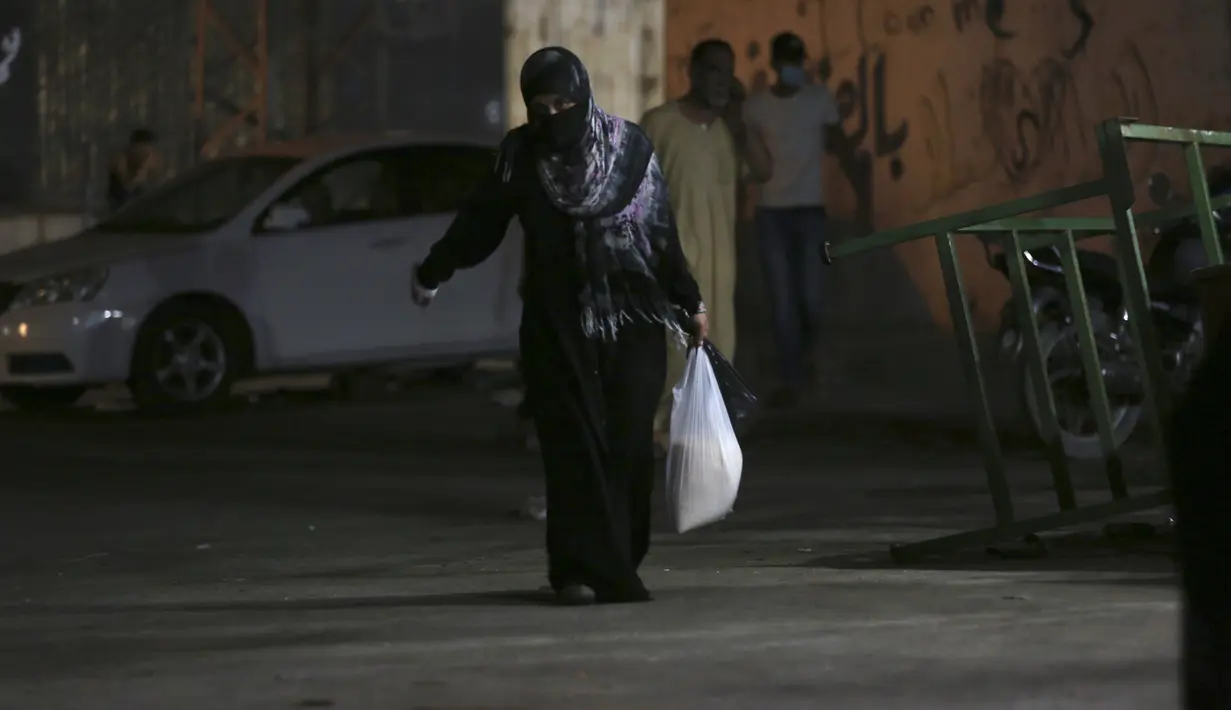 Seorang wanita mengenakan masker saat berbelanja di toko bahan makanan selama penguncian yang diberlakukan selama pandemi virus corona, di kamp pengungsi Shati, di Kota Gaza, Selasa, (1/9/2020). (AP Photo/Adel Hana)