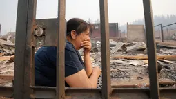 Warga duduk di sekitar puing-puing rumahnya yang terbakar di Santa Olga, Chile, (26/1). Kebakaran hutan yang terjadi dalam sepekan terakhir telah menghanguskan lahan seluas 155 kilometer persegi. (Javier Torres/Aton via AP)