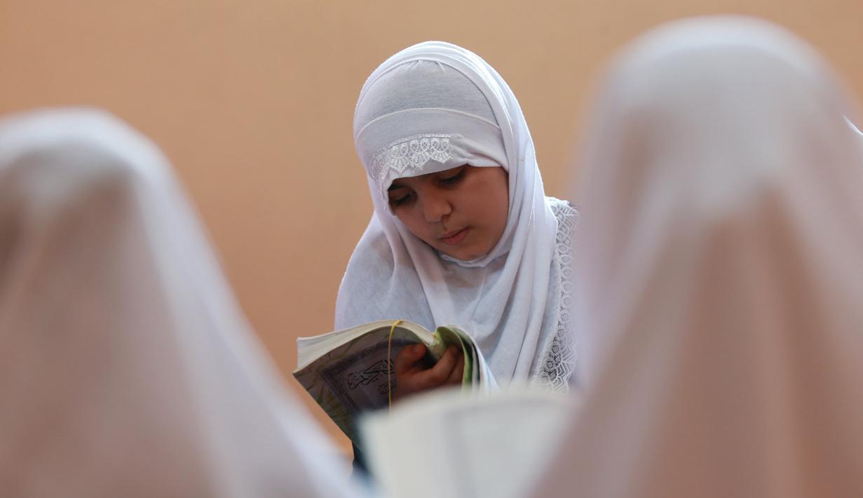 Seorang murid perempuan membaca kitab suci Alquran saat bulan suci Ramadan di sebuah sekolah di Benghazi, Libya, 5 Juli 2015. (REUTERS/Esam Al - Omran Fetori)
