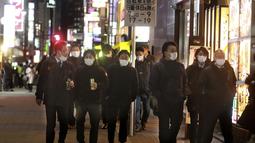 Orang-orang memakai masker untuk melindungi dari penyebaran virus corona berjalan di sepanjang jalan yang dipenuhi bar dan restoran di Tokyo, Rabu (19/1/2022). Para pemimpin lokal mempersingkat jam buka restoran, karena kasus omicron mencapai rekor tertinggi di ibu kota. (AP Photo/Koji Sasahara)