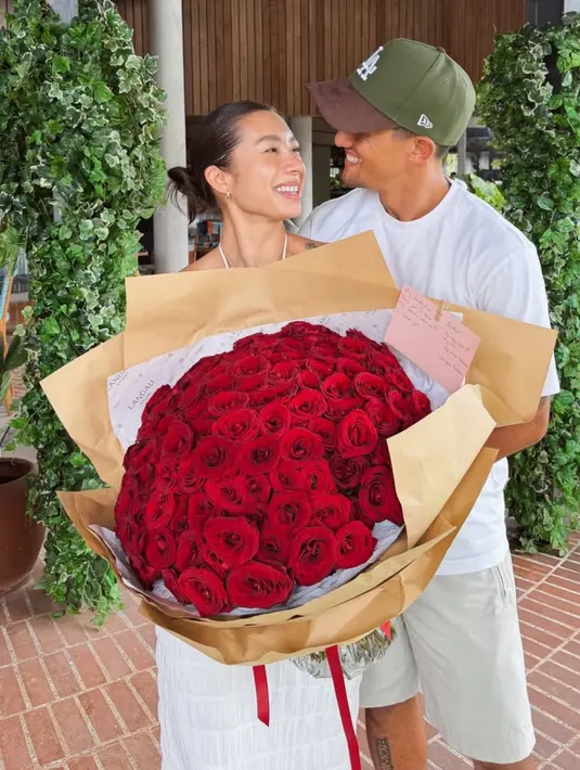 Jennifer Bachdim yang mengenakan dress putih halter neck menerima buket bunga mawar besar dari suaminya. [@jenniferbachdim]