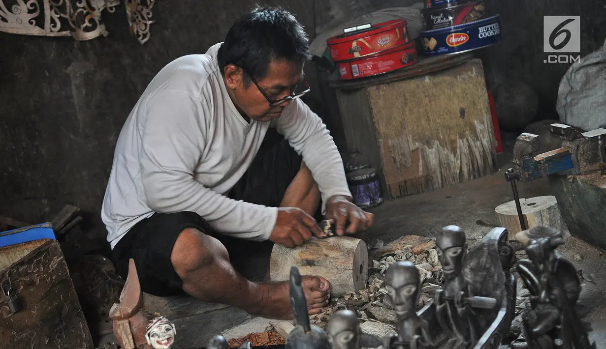 Perajin Oman Sumarna menyelesaikan pembuatan patung di Sanggar Primitif, Sawangan, Depok, Jawa Barat, Rabu (9/1). Harga patung-patung buatan Oman itu dijual dengan harga bervariasi tergantung tingkat kesulitan pembuatannya. (Liputan6.com/Herman Zakharia)