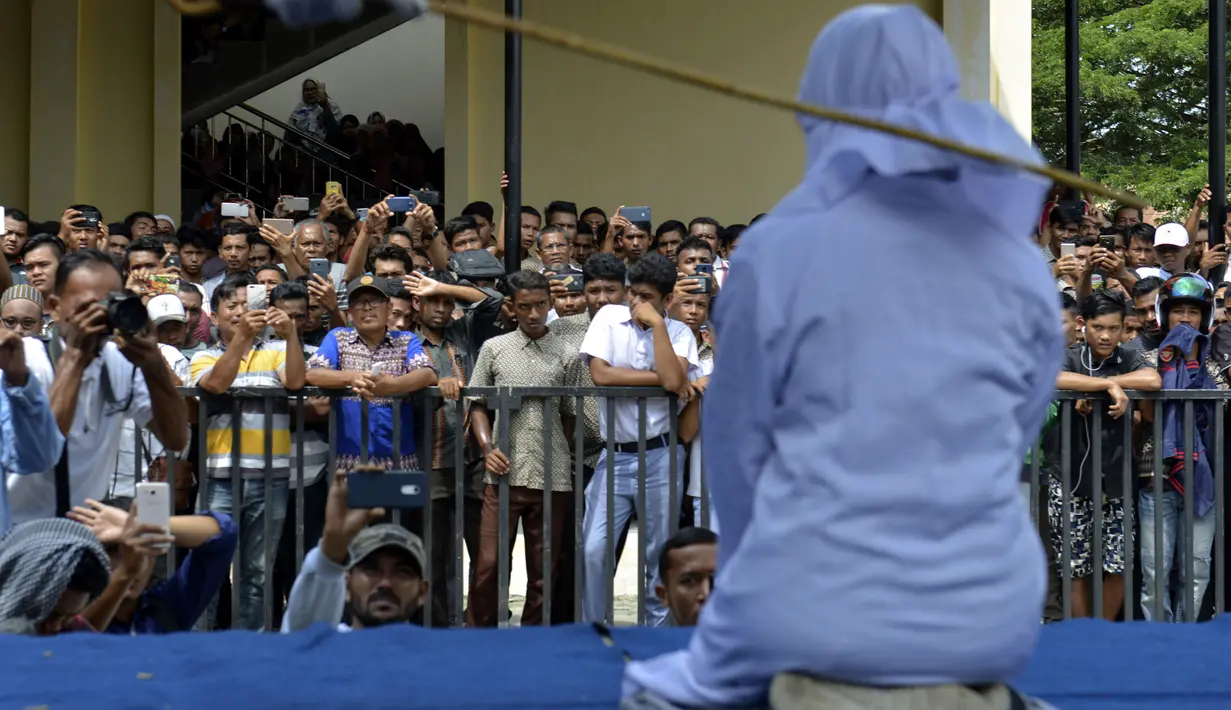 Seorang wanita berusia 19 tahun menjalani hukuman cambuk di depan umum di Banda Aceh (31/1). Dua remaja AS laki-laki (19) dan NS perempuan (19) dicambuk setelah mereka ketahuan berpelukan di depan umum. (AFP Photo/Chaideer Mahyudin)