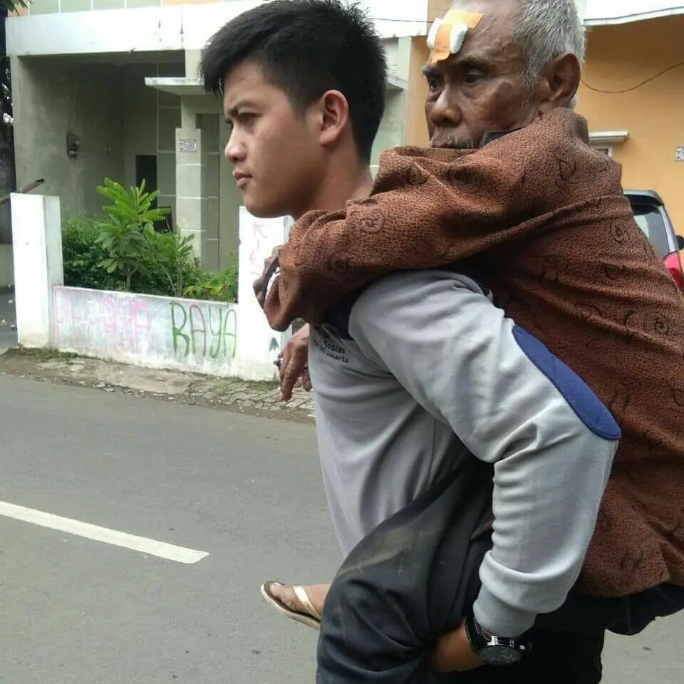 Petugas menggendong lansia tersebut saat mengantarkan ke rumahnya. (Istimewa)