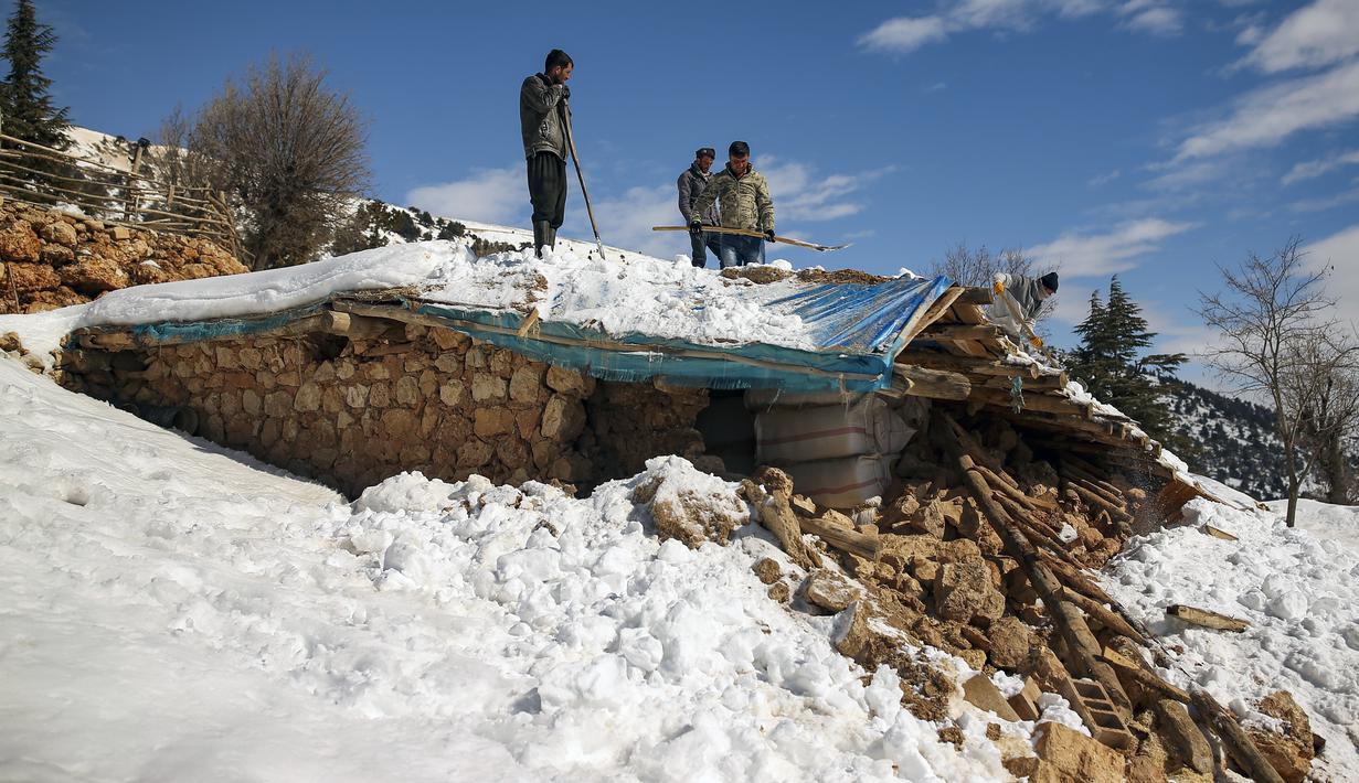 Penduduk desa berdiri di atas rumah yang runtuh di desa Buyuknacar di Kahramanmaras, Turki, Rabu, 15 Februari 2023. Sementara jumlah korban tewas hampir pasti akan meningkat lebih jauh lagi, banyak dari puluhan ribu korban selamat yang kehilangan tempat tinggal masih berjuang untuk memenuhi kebutuhan dasar, seperti mencari perlindungan dari hawa dingin yang menggigit. (AP Photo/Emrah Gurel)