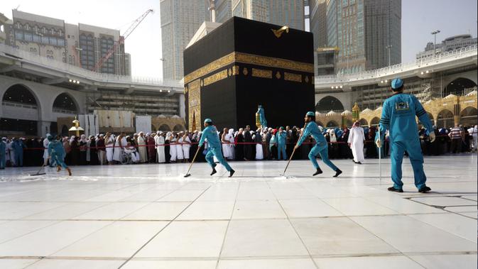 Para pekerja mensterilkan daerah di sekitar Kakbah di Masjid al-Haram, Makkah, Arab Saudi, Kamis (5/3/2020). Pemerintah Kerajaan Arab Saudi melalui  Wakil Menteri Kesehatan Abdel-Fattah Mashat melarang sementara penduduknya untuk melaksanakan ibadah umrah. (AP Photo/Amr Nabil)