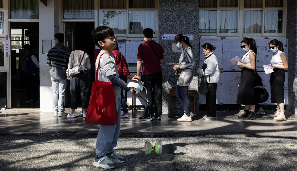 Seorang anak bermain ketika orang-orang mengantri untuk memberikan suara mereka dalam pemilihan presiden di sebuah tempat pemungutan suara di New Taipei City pada tanggal 13 Januari 2024. (Alastair PIKE/AFP)