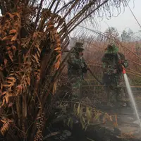 Personel TNI berupaya melakukan pemadaman di tengah pekatnya asap kebakaran lahan gambut di Kampar, provinsi Riau pada 17 September 2019. Kebakaran hutan dan lahan (karhutla) yang masih terjadi membuat sejumlah wilayah di Provinsi Riau terpapar kabut asap. (AP/Rafka Majjid)