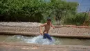 Seorang anak Palestina menikmati waktu bermain di sebuah mata air alami di tengah gelombang panas di Kota Jericho, Tepi Barat, (18/5/2020). (Xinhua/Luay Sababa)