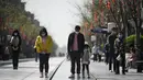 Orang-orang mengenakan masker membungkuk tiga menit selama peringatan nasional untuk memperingati korban meninggal dalam wabah virus coronavirus COVID-19 di sepanjang jalan bisnis di Beijing  (4/4/2020). (AFP/Wang Zhao)