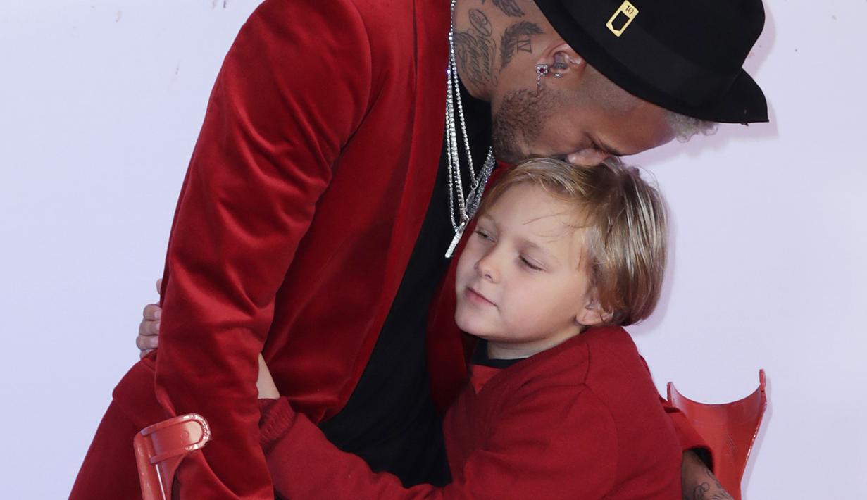 Pemain PSG, Neymar, mencium putranya saat merayakan pesta ulang tahun di Paris, Senin (4/1). Penyerang asal Brasil itu merayakan hari jadi yang ke-27 tahun dengan keadaan cedera. (AFP/Thomas Samson)