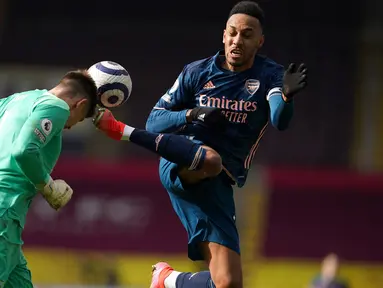 Kiper Burnley, Nick Pope menanduk bola dari ancaman striker Arsenal, Pierre-Emerick Aubameyang dalam laga lanjutan Liga Inggris 2020/21 di Turf Moor, Burnley, Sabtu (6/3/2021). Burnley bermain imbang 1-1 dengan Arsenal. (AFP/Jon Super/Pool)