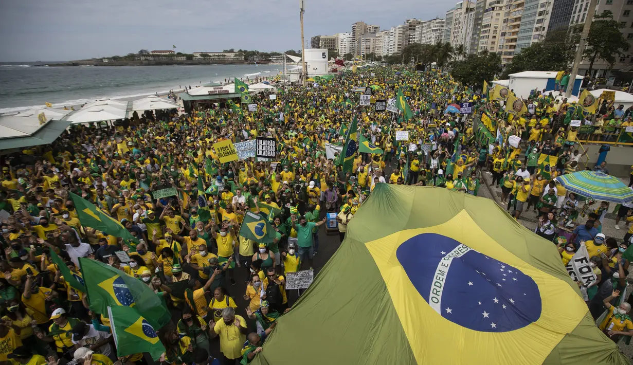 Pendukung Presiden Brasil Jair Bolsonaro membawa bendera nasional di sepanjang Pantai Copacabana pada Hari Kemerdekaan di Rio de Janeiro, Selasa (7/9/2021). Ribuan orang tersebut terbagi dalam dua kubu yaitu pendudukung serta penentang Presiden Brasil Jair Bolsonaro. (AP Photo/Bruna Prado)