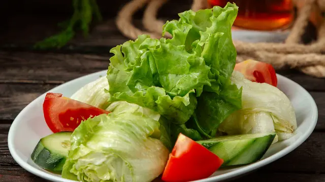 Sepiring salad sayur-sayuran di atas meja yang terdiri dari selada, timun, dan tomat (Foto Dok: Freepik/KamranAydinov)
