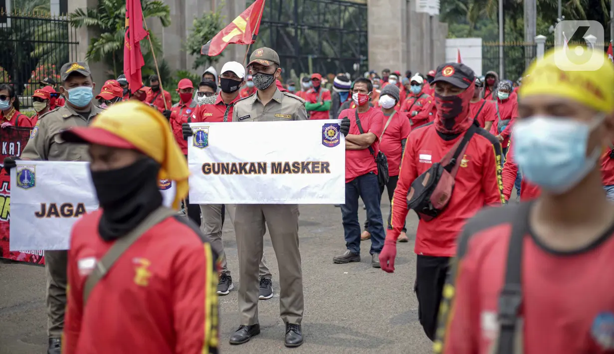 Petugas Satpol PP memegang poster imbauan protokol kesehatan COVID-19 saat unjuk rasa buruh di depan Gedung DPR, Jakarta, Selasa (17/11/2020). Pemerintah terus mengingatkan pentingnya 3M yaitu memakai masker, menjaga jarak, dan mencuci sebagai upaya pencegahan Covid-19. (Liputan6.com/Faizal Fanani)
