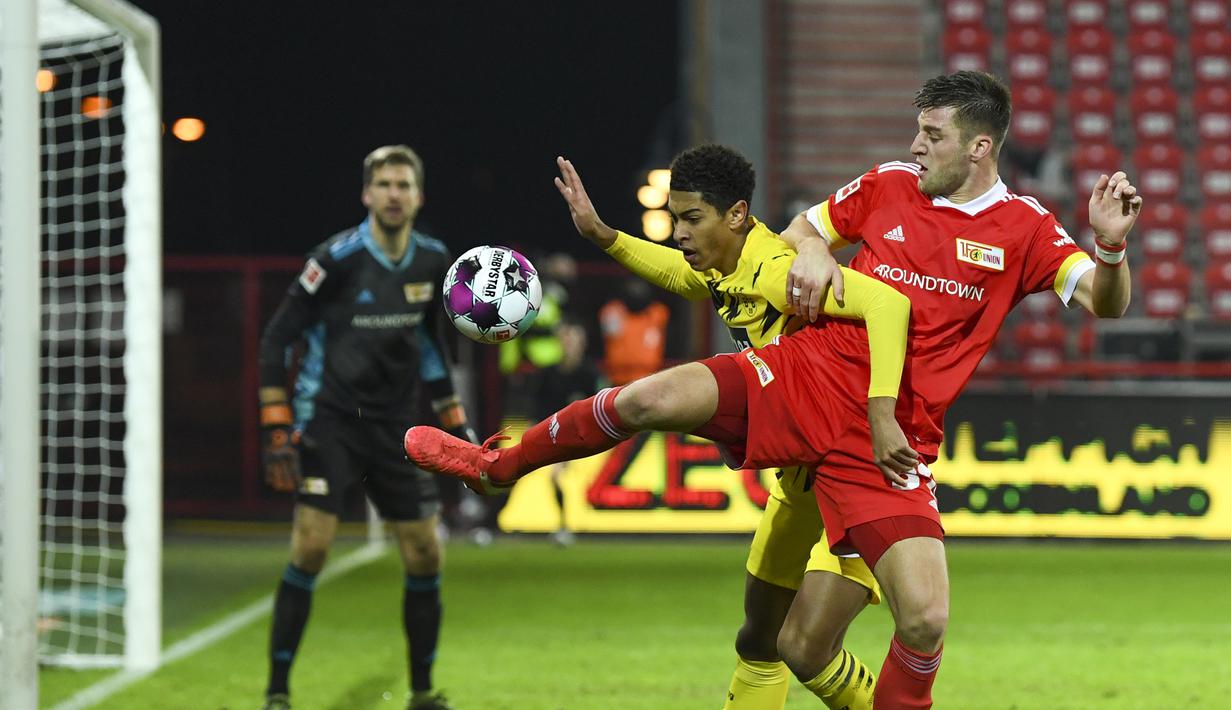 Gelandang Borusia Dortmund, Jude Bellingham, berebut bola dengan bek Union Berlin, Robin Knoche, pada laga lanjutan Liga Jerman di Stadion Alte Forsterei, Sabtu (19/12/2020) dini hari WIB. Borussia Dortmund kalah 1-2 melawan Union Berlin. (AFP/Annegret Hilse/pool)