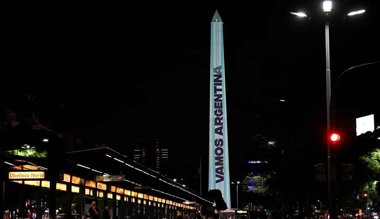 Video mapping  menunjukkan bendera nasional dan tanda bertuliskan: "Go Argentina!" di Obelisk di Buenos Aires, Senin (21/11/2022). Proyeksi cahaya tersebut sebagai bentuk untuk menyemangati timnas Argentina sebelum menghadapi Arab Saudi dalam laga pertama Grup C Piala Dunia 2022, Selasa (22/11/2022) petang WIB. (Luis ROBAYO / AFP)