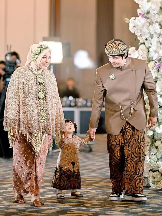 Sedangkan untuk upacara Siraman di acara Mitoni baby number 2, Aurel dan Atta tampil menggemaskan menggandeng baby Ameena dengan busana adat Jawa bernuansa cokelat. [Foto: Instagram/attahalilintar]