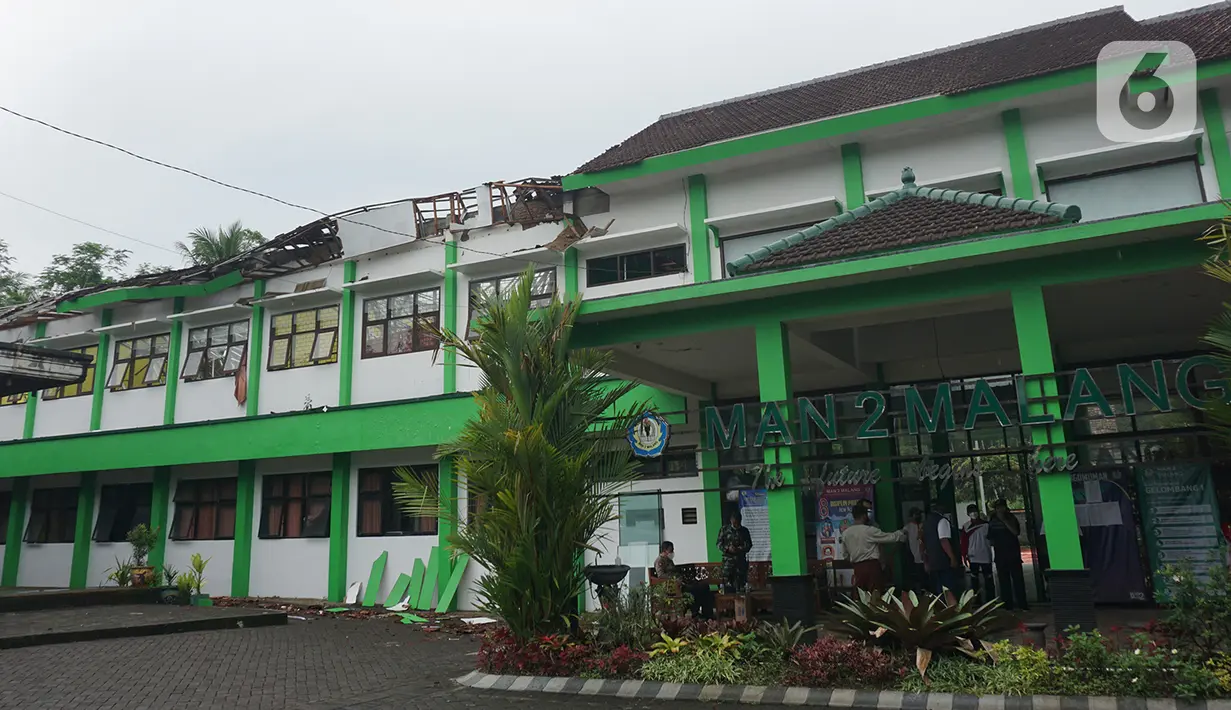 Sejumlah petugas berada di depan MAN 2 Malang yang rusak akibat gempa di Turen, Kabupaten Malang, Minggu (11/4/2021). Kejadian ini juga membuat 36 laptop, 25 PC, 20 set meja bahasa rusak. Sementara, seorang staf sekolah mengalami luka ringan setelah tertimpa genteng. (merdeka.com/Nanda F. Ibrahim)