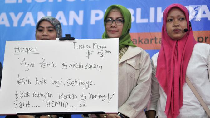 Istri almarhum Ketua KPPS Bekasi Masnun (kanan) dan petugas KPPS Tanjung Priok Tursina Maya (tengah) berfoto di depan kanvas berisi harapan untuk Pemilu yang akan datang saat acara Ngopi Bareng Ombudsman di Ruang Serbaguna Ombudsman RI, Jakarta, Selasa (30/4/2019). (merdeka.com/Iqbal Nugroho)