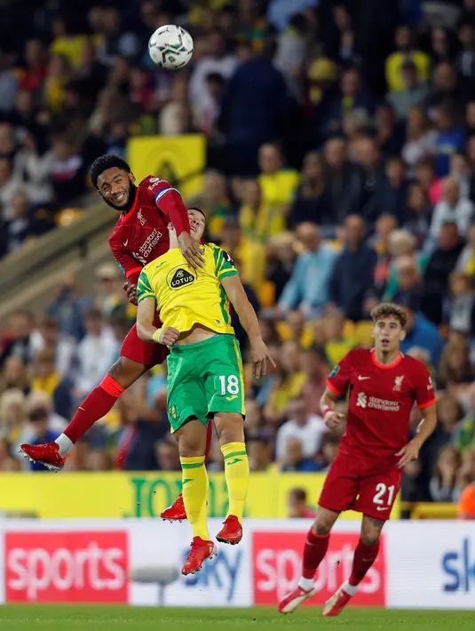 Bek Liverpool Joe Gomez menyundul bola saat bersaing dengan gelandang Norwich City Christos Tzolis pada babak ketiga Piala Liga Inggris di Carrow Road, Rabu (22/9/2021) dinihari WIB. Liverpool sukses menghajar Norwich City tiga gol tanpa balas di kandang lawan. (ADRIAN DENNIS / AFP)